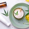 Cosmetics with cannabis oil on a turquoise plate on a light marble background. Concept of luxury skin care.